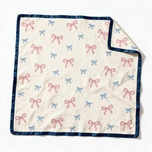 JOWI Baby Blanket shown flat from the front, cream ground, small scattered bows, navy satin binding