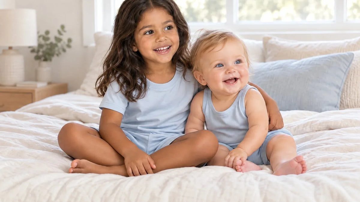 A four-year-old and her baby sister on the bed, sharing one colour and nothing else.
