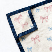 Close up photograph of the JOWI Baby Blanket on white: the corner where two edges of the navy satin binding are mitred together, with the corner turned back