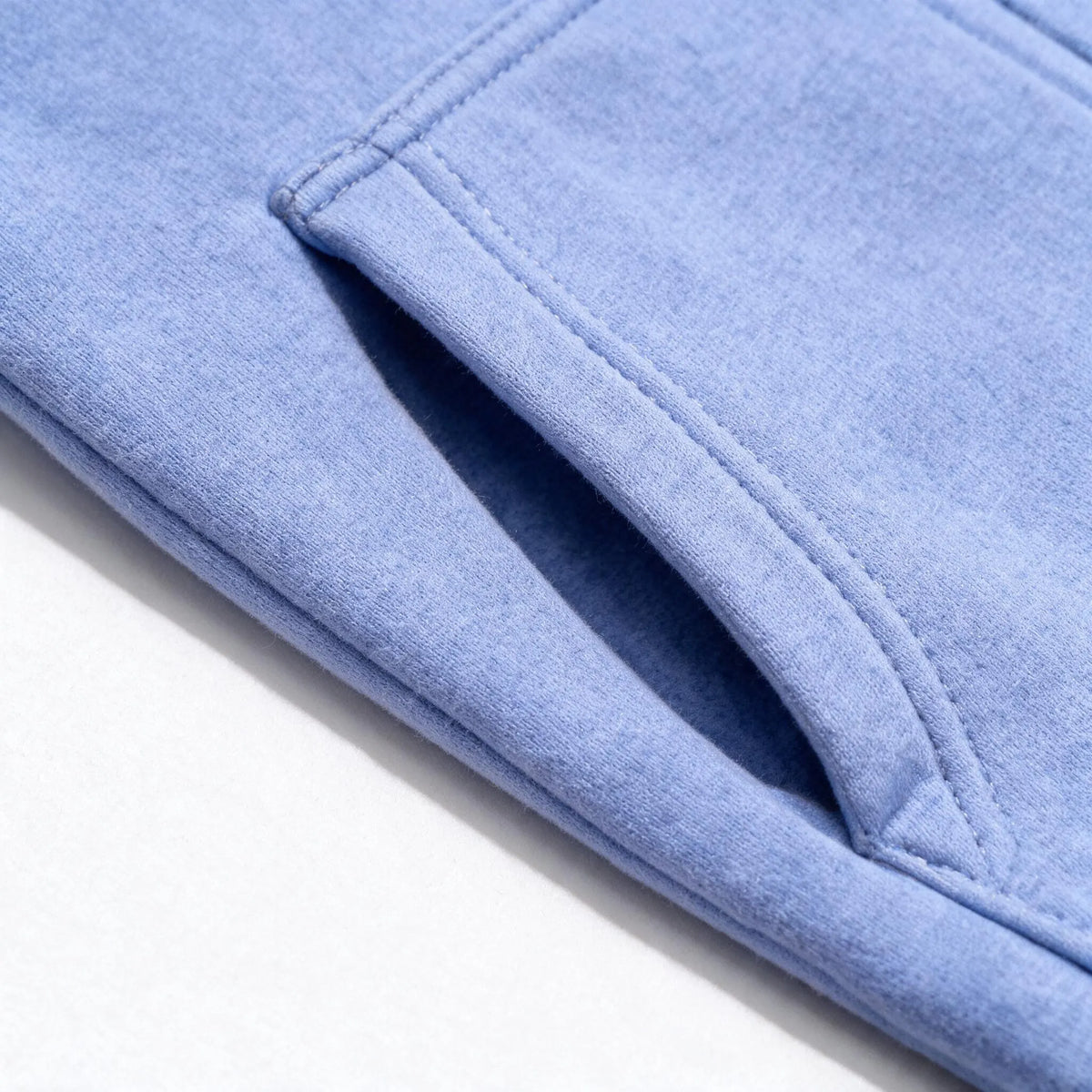 Close up photograph of the JOWI Blue Daisy Hoodie & Jogger Set on white: the slanted opening of one front pouch pocket, with its topstitching and corner bar tack