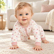 A baby moving and playing in the JOWI Blush Floral Romper in daylight at home