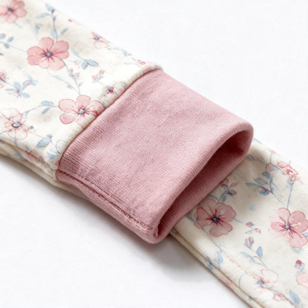 Close up photograph of the JOWI Blush Floral Romper on white: the wide fold over cuff turned back on itself over the printed cloth