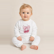 Toddler girl sitting in the JOWI Cherry Bow Sweatshirt & Jogger Set, size 12-24 months