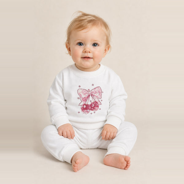 Toddler girl sitting in the JOWI Cherry Bow Sweatshirt & Jogger Set, size 12-24 months