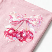 Close up photograph of the bow tied over two cherries on the chest of the JOWI Cherry Bow Tee & Short Set, with the cotton jersey at true scale