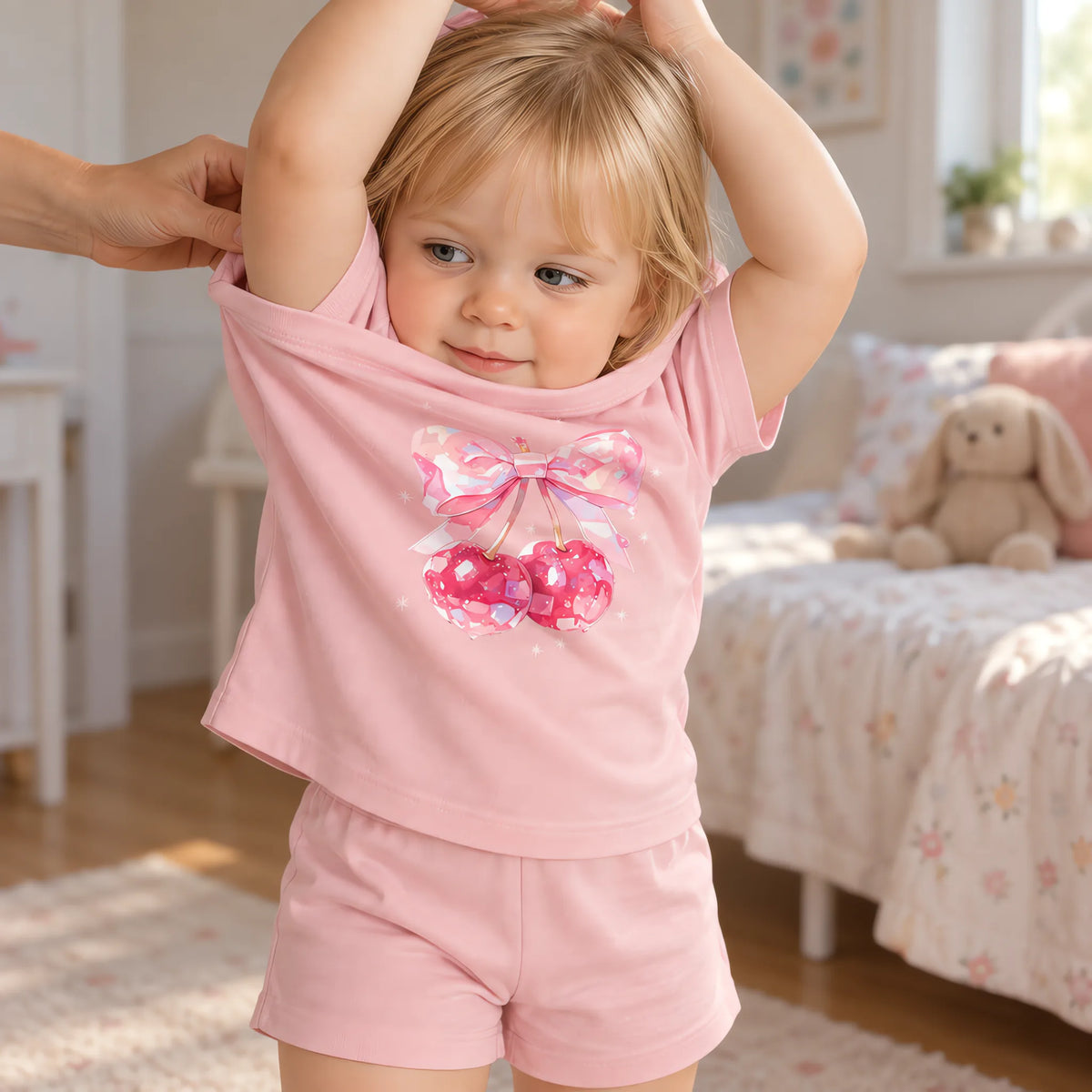 A girl pulling the tee of the JOWI Cherry Bow Tee & Short Set on over her head, showing that it has no fastening