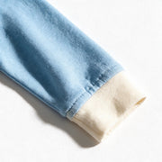 Close up photograph of the JOWI Cloud Blue Baby Romper on white: the plain cream ribbed cuff against the unprinted blue knit