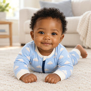 A baby moving and playing in the JOWI Cozy Cloud Sleepsuit in daylight at home
