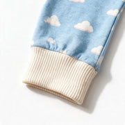 Close up photograph of the JOWI Cozy Cloud Sleepsuit on white: the plain cream ribbed cuff that closes the cloud print, with no foot beyond it