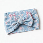 Blue rose toile bow headband photographed flat on white, showing the soft knotted bow and the stretch of the printed jersey band