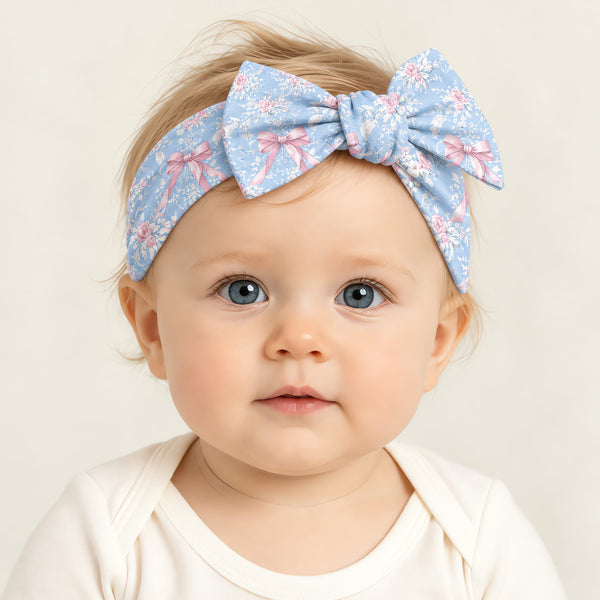 Baby wearing the blue rose toile bow headband over a plain cream bodysuit