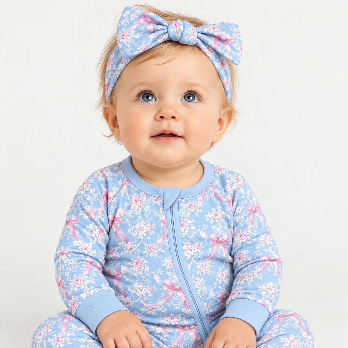 Baby wearing the bow headband with the matching blue rose toile zip romper