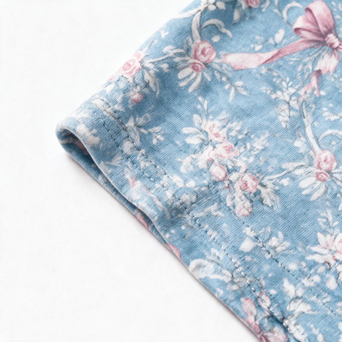 Close up photograph of the JOWI Blue Rose Toile Bow Headband on white: the hemmed and topstitched edge of the wide printed band, lying soft and flat