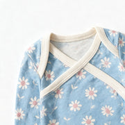 Close up photograph of the JOWI Little Daisy Bodysuit on white: the envelope neckline, with the two shoulder panels crossing over each other under their plain cream bands