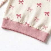Close up photograph of the JOWI Pink Bow Baby Set on white: the plain dusty pink ribbed hem band at the bottom of the top