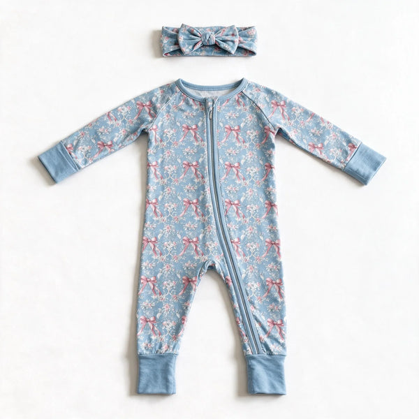 Blue rose toile zip romper photographed flat on white with the matching bow headband above it, showing the two way zipper and the plain blue cuffs