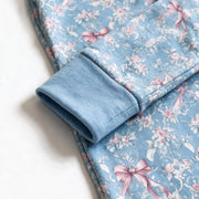 Close up photograph of the JOWI Blue Rose Toile Zip Romper on white: the wide plain blue fold over cuff turned back on itself over the rose toile print