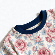 Close up photograph of the JOWI Rose Garden Pajama Set on white: the plain navy ribbed crew neckband of the top