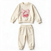 Cream cherry bow sweatshirt and matching joggers photographed flat on white, with the pink sequin bow and cherries on the chest and the sleeves plain