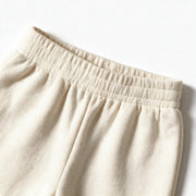 Close up photograph of the JOWI Cherry Bow Sweatshirt & Jogger Set on white: the flat elastic waistband of the cream joggers, with the terry gathered softly below it